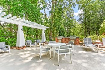A patio with a table and chairs under a white pergola. at Southpark Commons Apartment Homes, Charlotte, NC, 28210